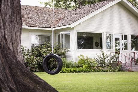 A single family home with a tire swing outside.