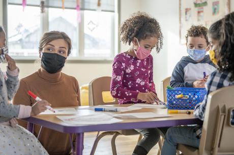 A table of school aged children around a desk. 