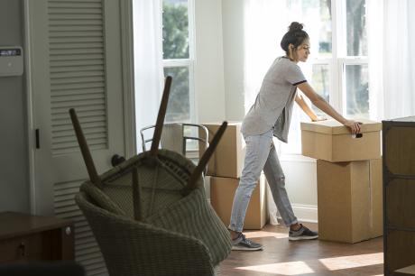 A woman in her home surrounded by moving boxes.