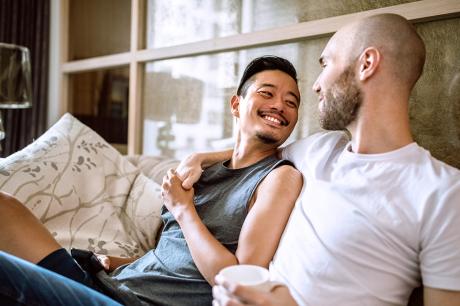 Two men hugging each other while they sit on a couch.