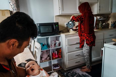 Two parents  in their home holding their baby.