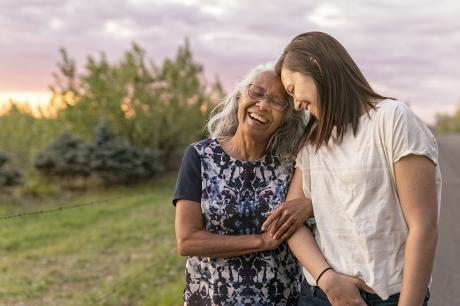 An older woman and her daughter walking outside.