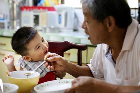 A dad feeding his son. 
