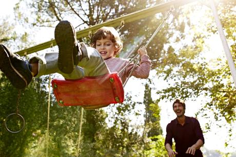 A father pushing his son on a swing.