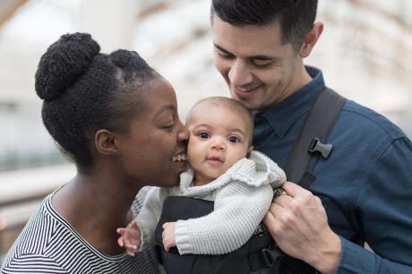 A couple kissing and hugging their baby.