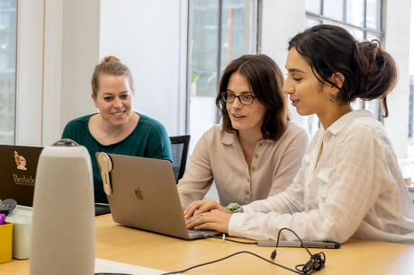 photo of people sitting together looking at laptop