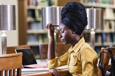 A young woman working at a desk in a library.