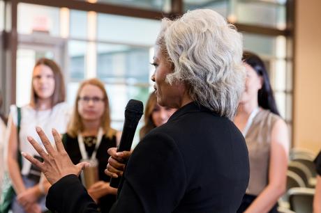 An older black woman speaking at an event.