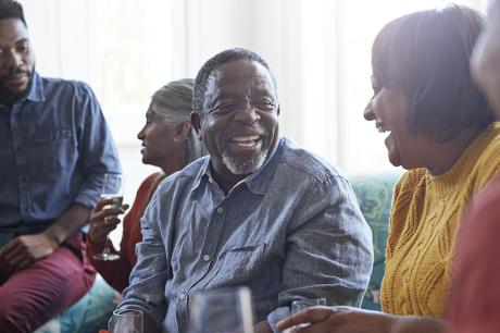 A black men laughing among a group of people.