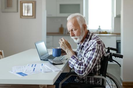 An older man in a wheelchair looking over bills.