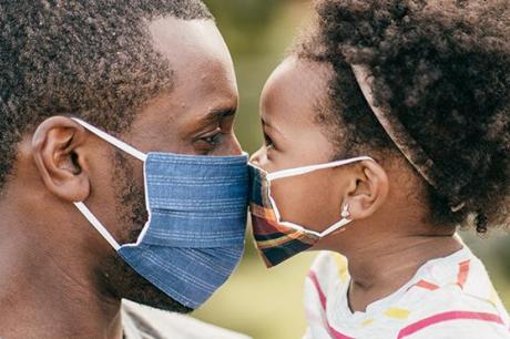 photo of parent and child wearing masks and putting faces together 