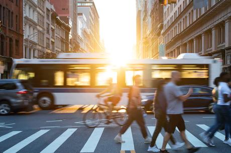 People walking at a cross walk in a city.