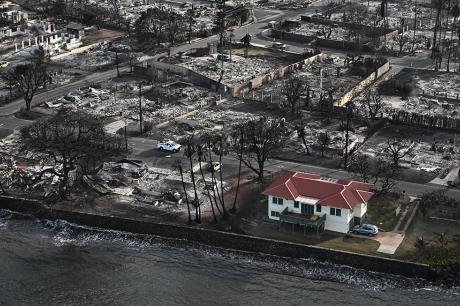 An aerial image shows a red roofed house that survived the fires surrounded by destroyed homes and buildings burned to the ground in the historic Lahaina in the aftermath of wildfires in western Maui in Lahaina, Hawaii.