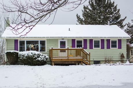 The front of a single family home with snow on the ground.