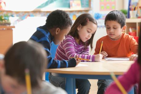 school aged children at their desks working on school work.
