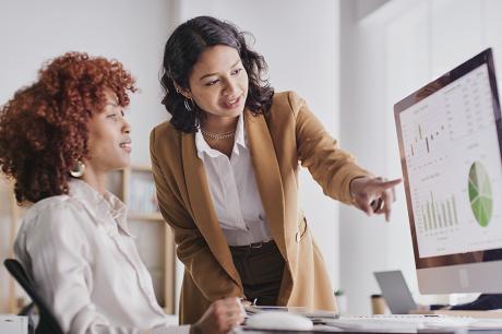 Two women at work looking at a desktop screen.