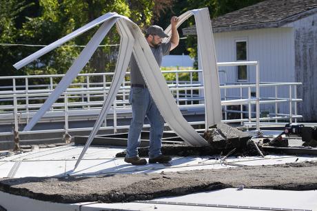 Elijah Lemieux, of the Vermont Rural Water Association, cleans up debris that was left by rising waters over the wastewater clarifier at the treatment plant following July flooding.