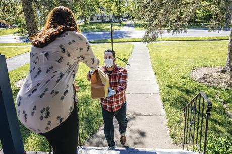 A woman receiving a food delivery at her front door.