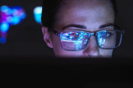 A person's face illuminated by a computer screen.