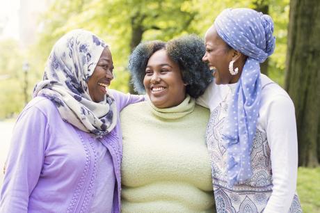 A group of black women of different ages hugging outside.