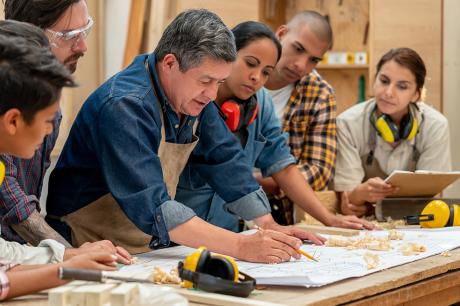 photo of Group of Latin American workers at a factory making furniture and looking at a blueprint - manufacturing concepts