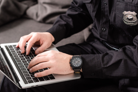 photo of cropped view of policeman typing on laptop keyboard
