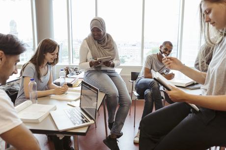 photo of smiling multi-ethnic friends discussing over project in classroom at university