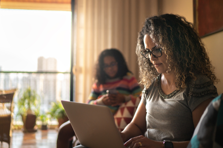 A woman working on her laptop in her living room.