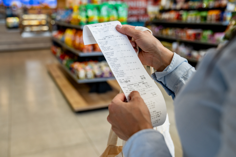 A woman looking at a grocery reciept.