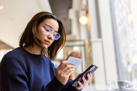 A young woman uses a credit card to make a purchase on her phone.