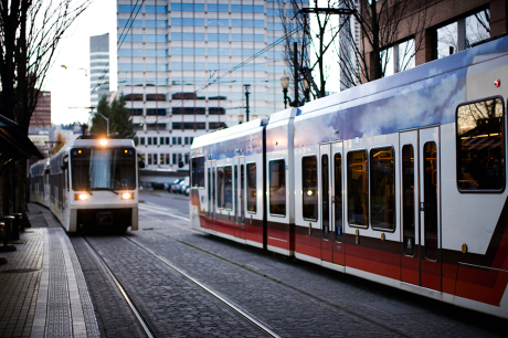 Two public transit trains passing through a city.