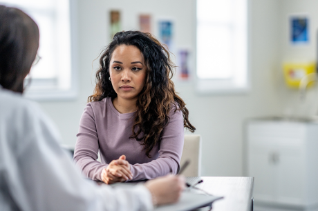 young woman of mixed race, sits with her female doctor as they discuss her health