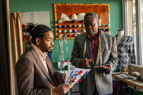 afrolatin senior tailor working with client in studio