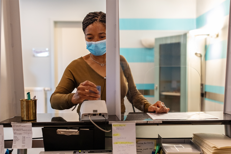 Woman wearing a mask at a reception desk.