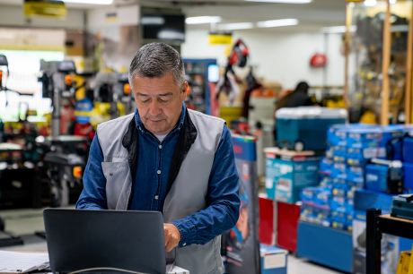 An older man checks his laptop at work.