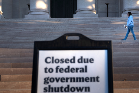 A woman walks past a sign indicating the National Gallery of Art is closed during the government shutdown