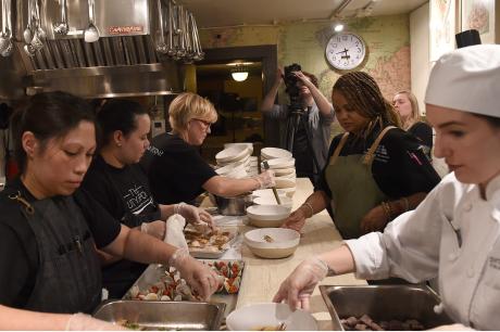 Restaurant workers gather around a table and plate food