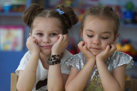 Two children hold their heads in their hands, one looks at the camera