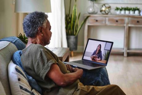 Photo of an older Black woman on a video call with a health care provider.