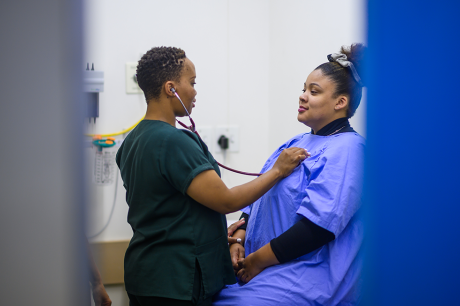 A doctor holds a stethoscope to her patient's chest