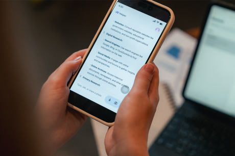 A person holds a smartphone displaying an “AI Helper” chat screen