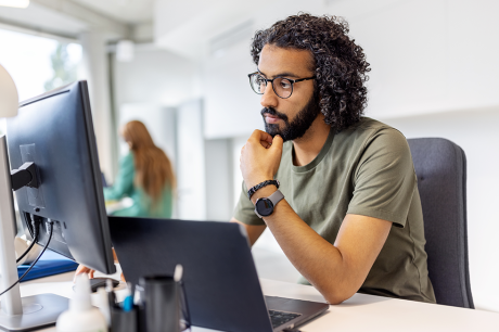 Image of a young worker of color looking at a computer screen.