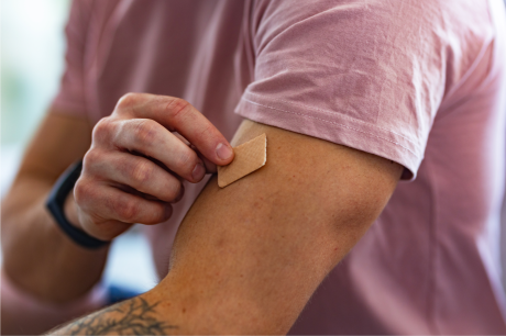 An adult placing a nicotine patch on their arm.