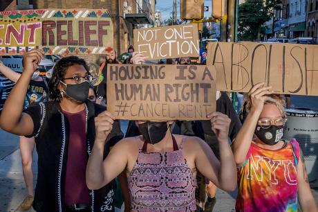 Protesters hold "abolish rent" and "rent relief" signs
