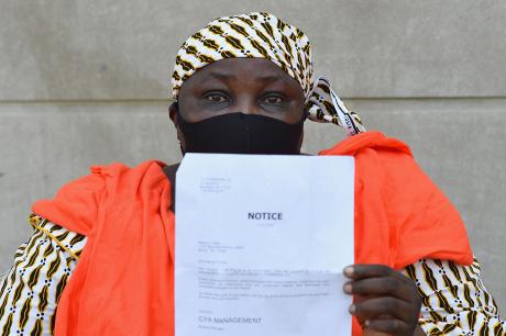 Woman holds up a notice to pay an outstanding rent balance