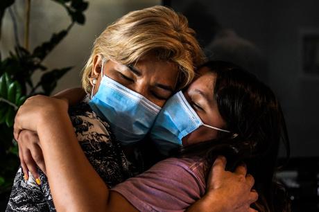 Two women hug while wearing masks