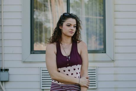 Woman stands in front of her house