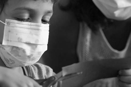 Child does crafts while wearing a mask