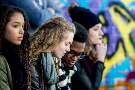 Teenagers hang out beside a mural