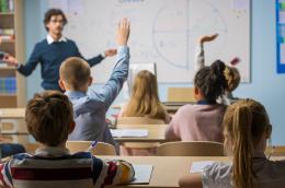 A teacher asks a question and several students raise their hands